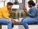 Two people sit on a bench while using their devices