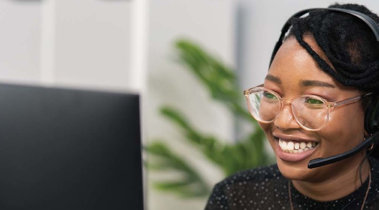 Image of a woman wearing a headset in front of a computer screen