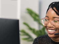 Image of a woman wearing a headset in front of a computer screen