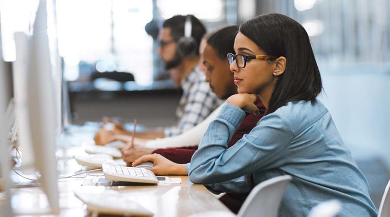 Students use desktop computers in a room