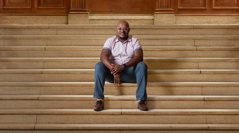 Curtis Cain sits on the steps of a building at Howard University