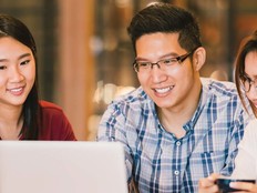 Three students look at a laptop