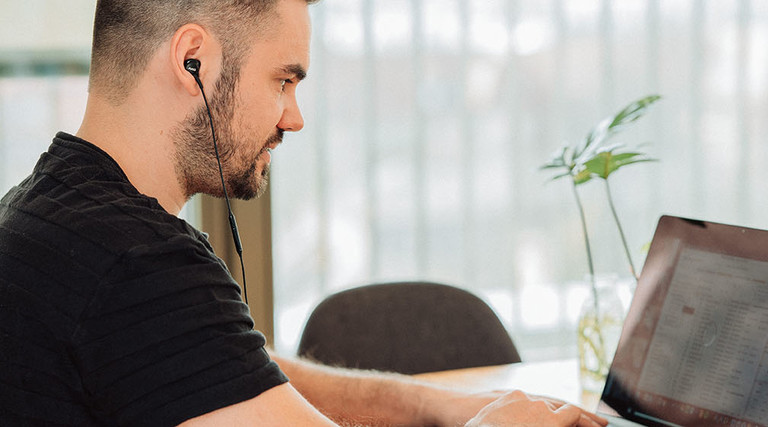 man wearing headphones on laptop