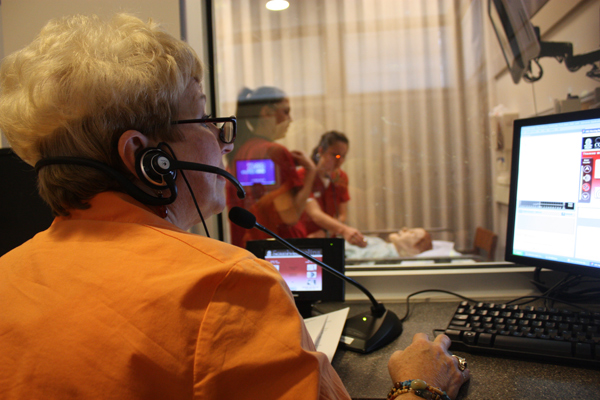 As part of the cardiac arrest simulation, Clinical Professor Lydia Zager (foreground) speaks for the patient as students Katheryn Niswanger (left) and Rachael McElvie (right) respond. 