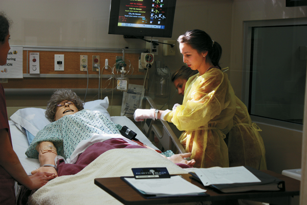 Students Monica Shull (right) and Samantha Osman (background) test a patient’s vital signs.