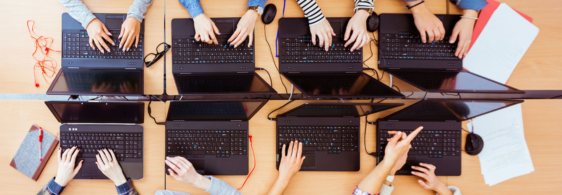 Top view of female students learning computer programming. Girls in computer lab coding on laptops.