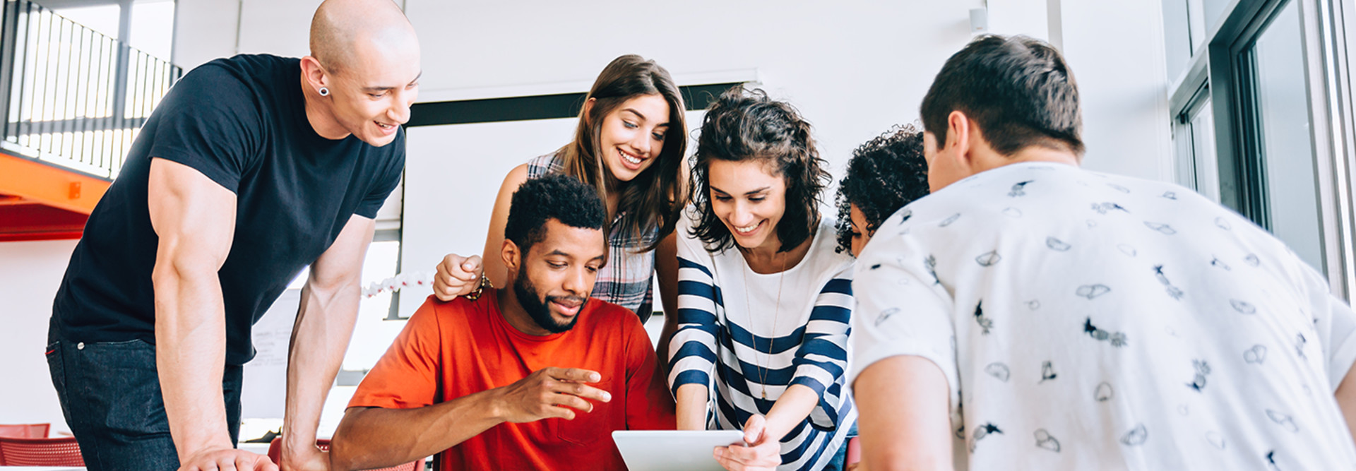 Students around a desk looking at a device