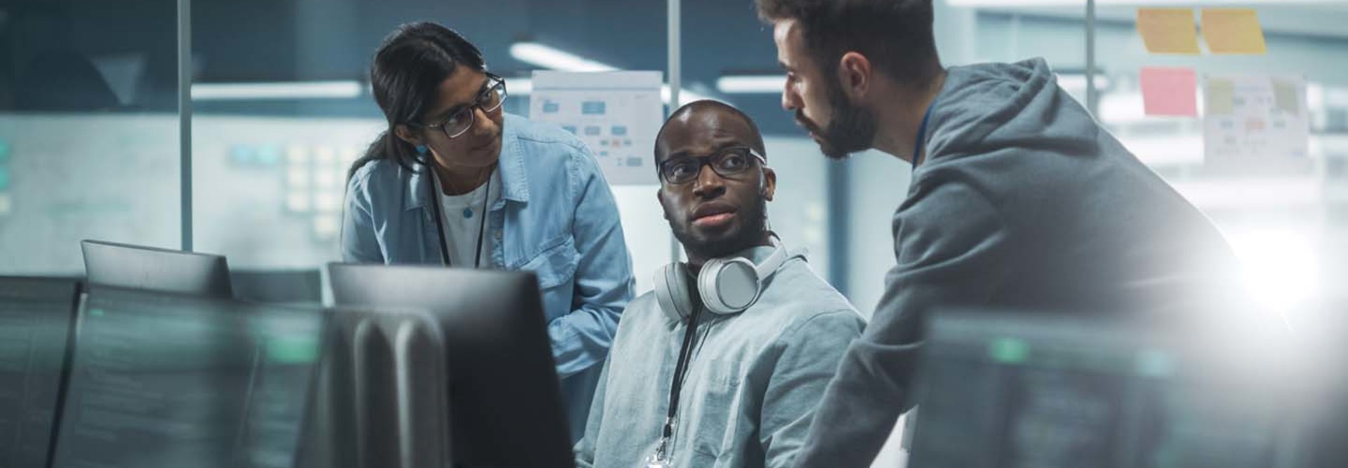 A group of professionals discuss something around some computers