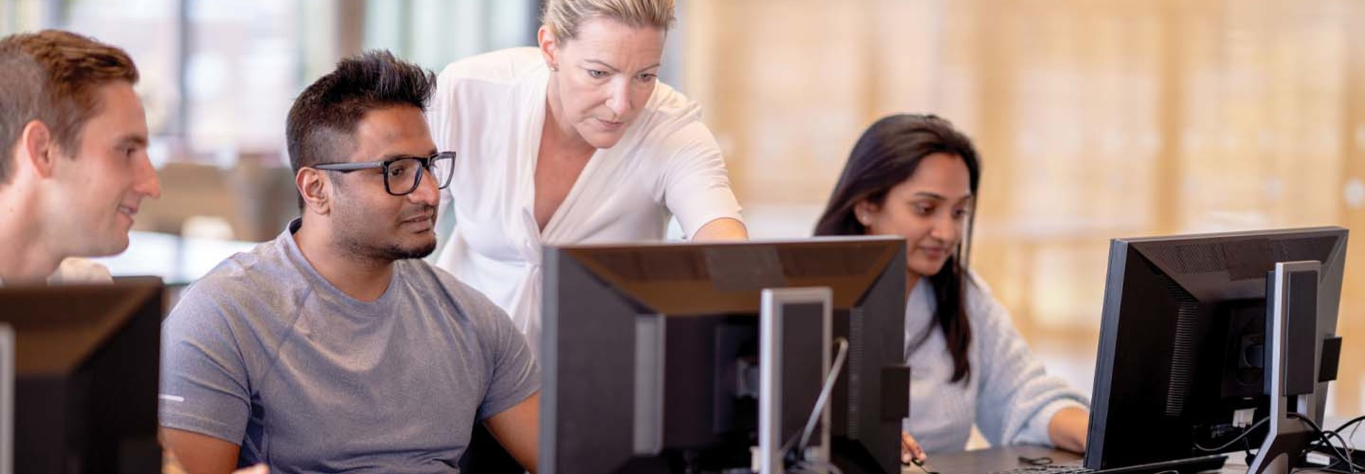 A group of people work at a computer lab