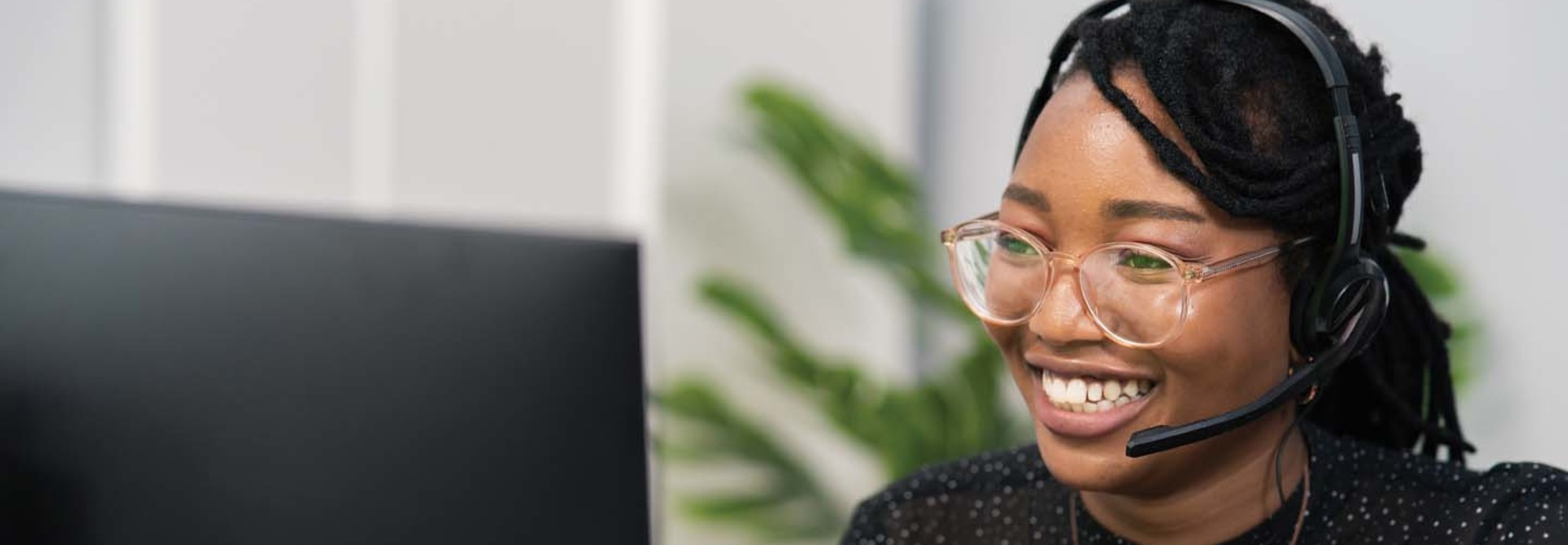 Image of a woman wearing a headset in front of a computer screen