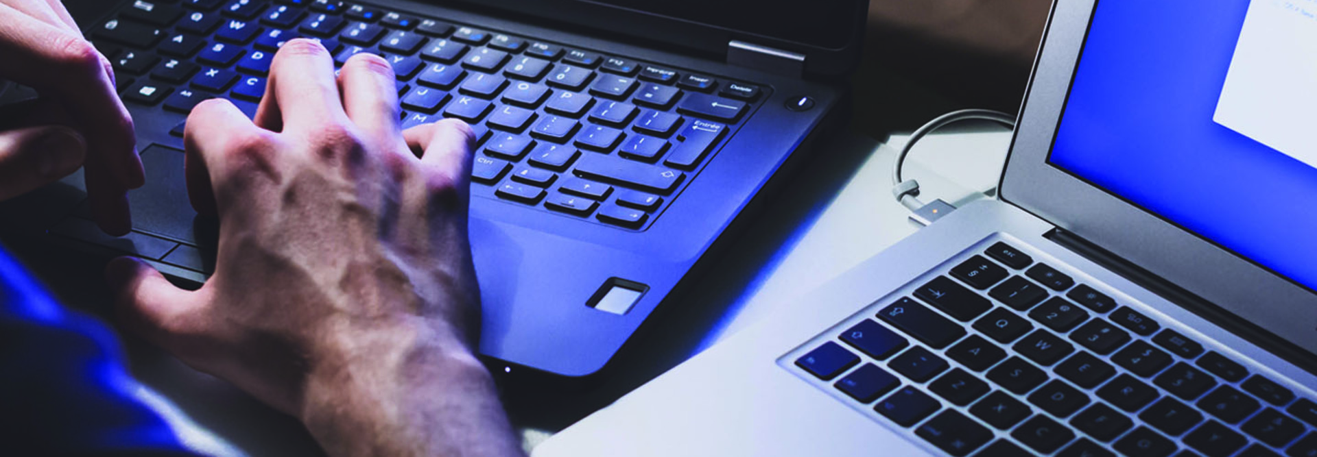 Hands working on two laptops