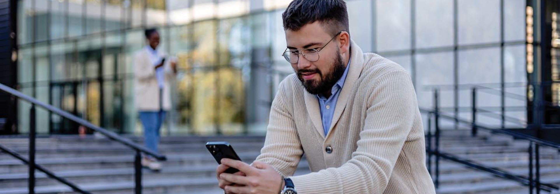 A man looks at his phone in front of a building