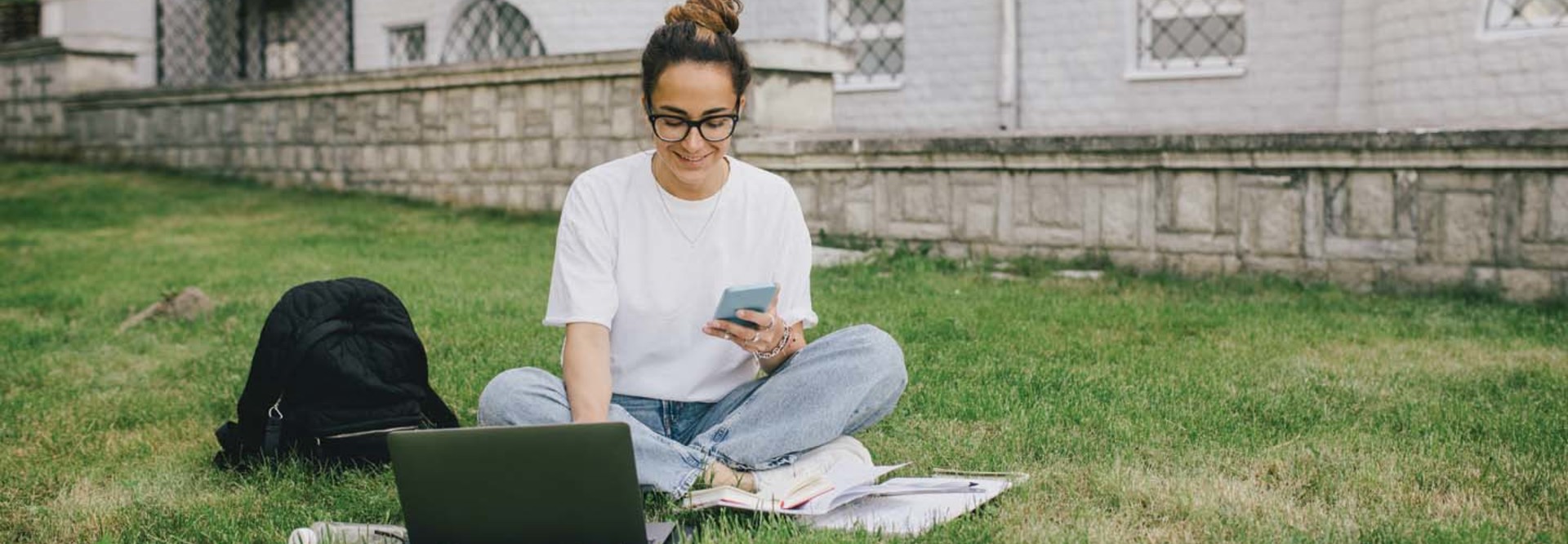 A woman uses a laptop on a college campus