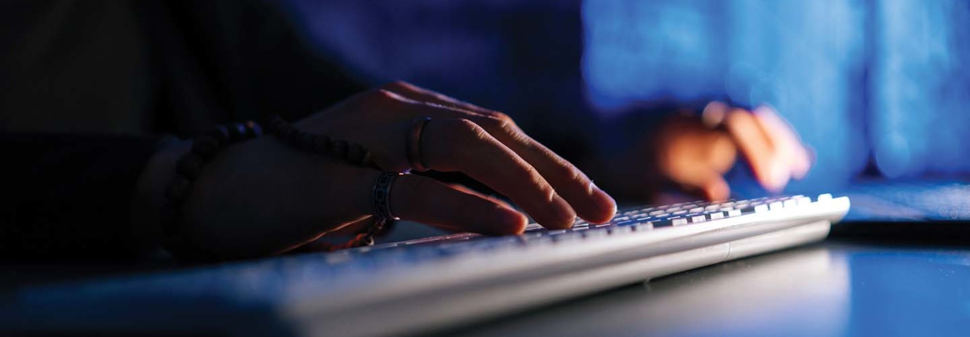 Hands on a keyboard in a dimly lit room