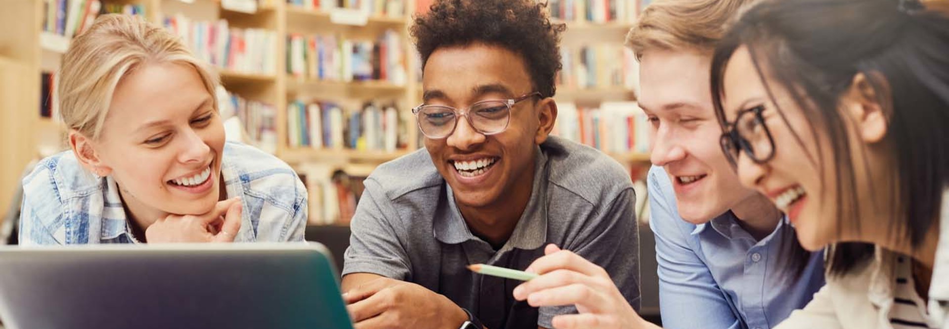 Several students look at a laptop together