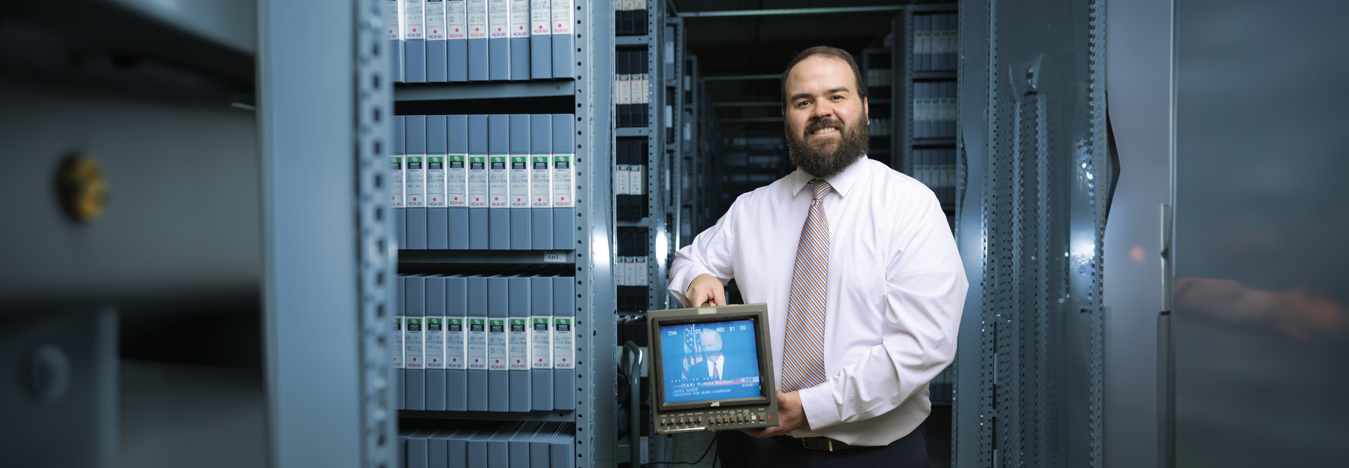 Photograph of Jim Duran holding a small television at the Vanderbilt Television News Archive