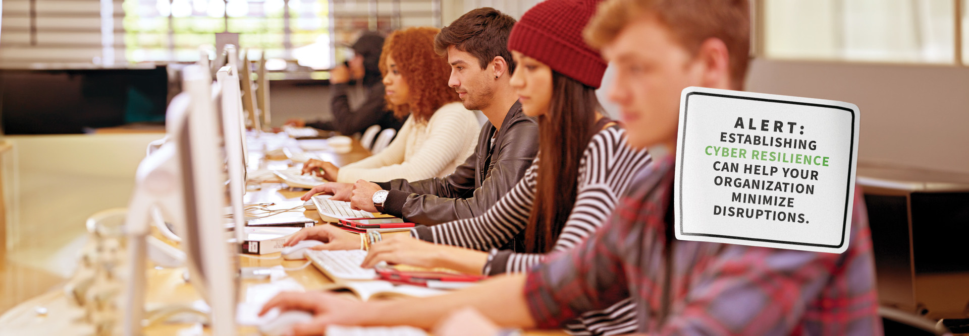 Students sit at a table and use their computers