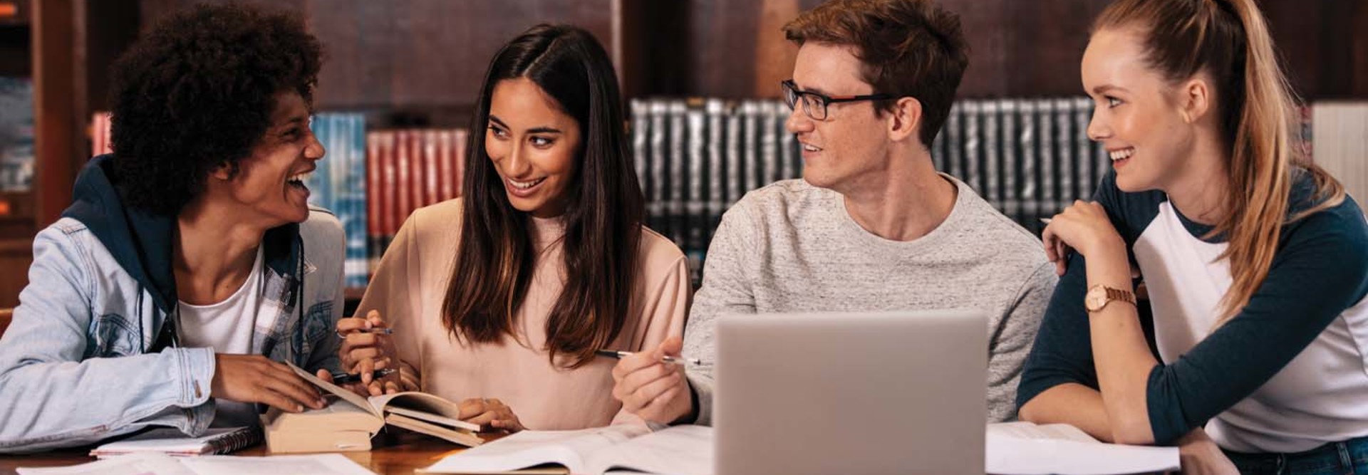 Four college students chat near a computer