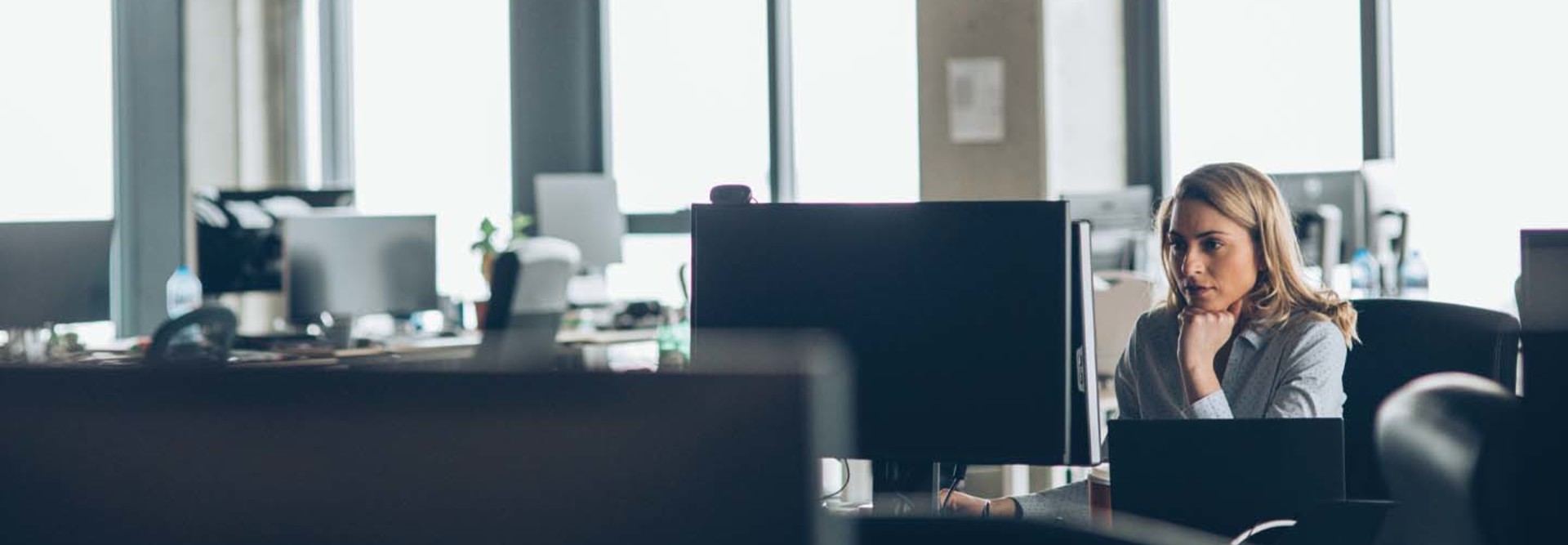 A woman works at a desk in a mostly empty office