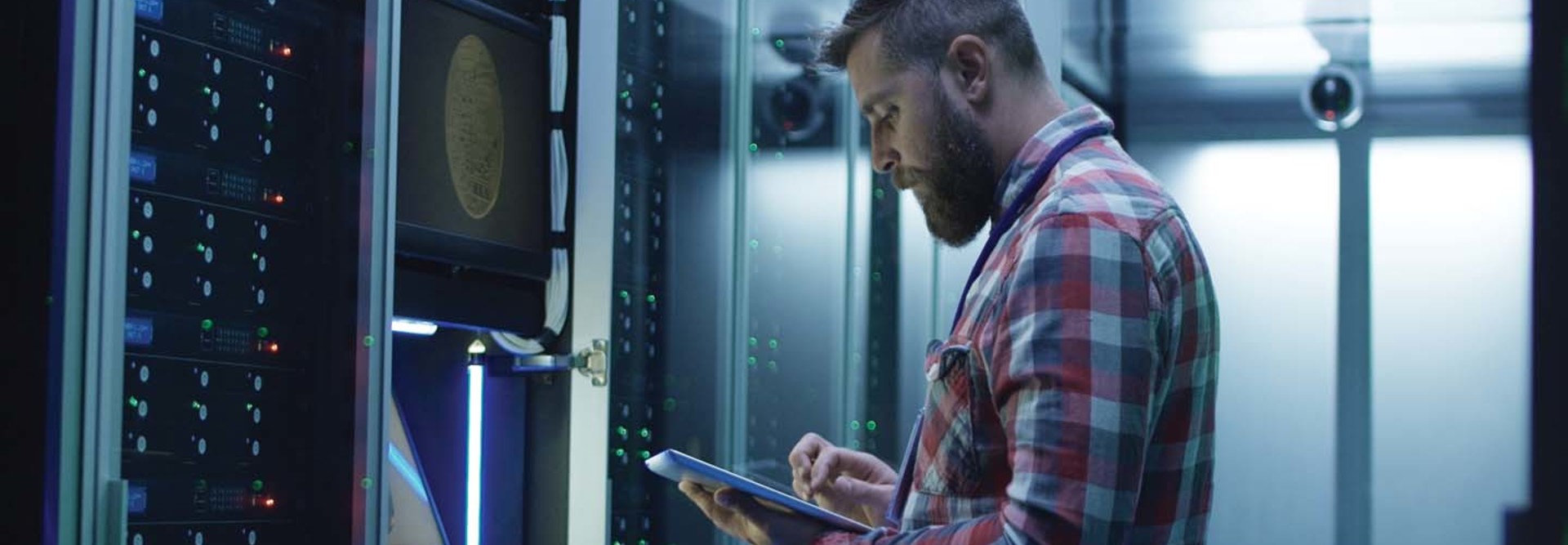 A man works on a tablet inside a large data center