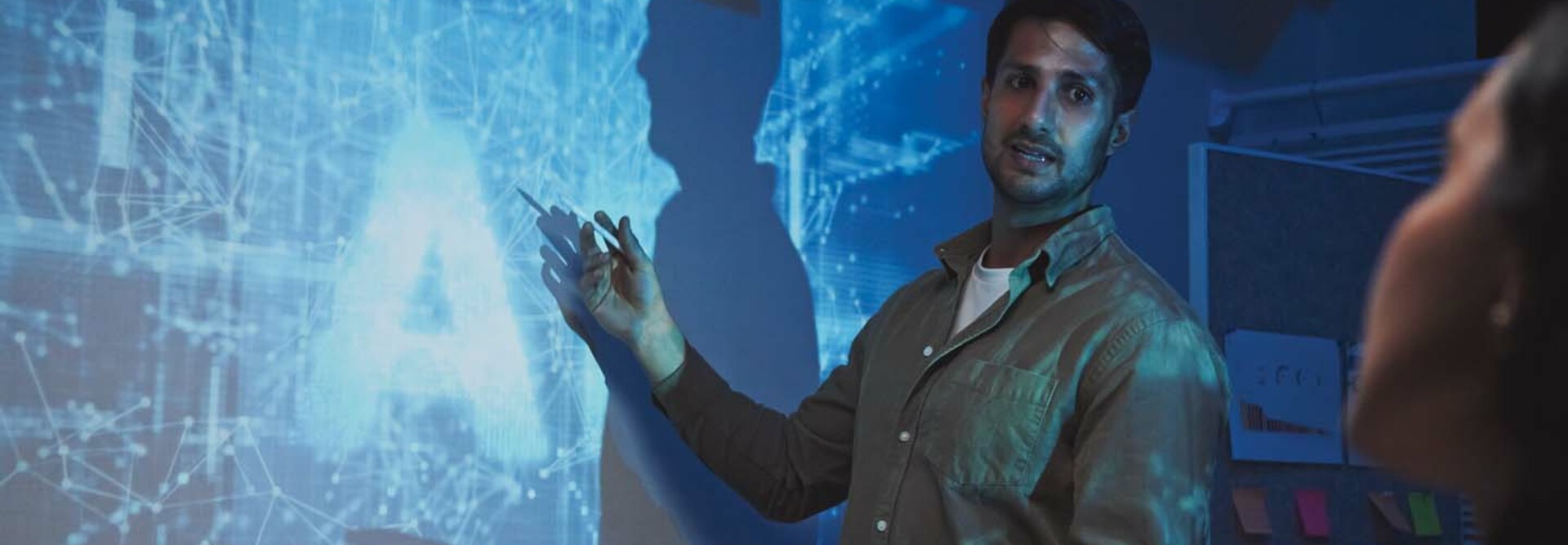 A man stands in front of an abstract representation of artificial intelligence