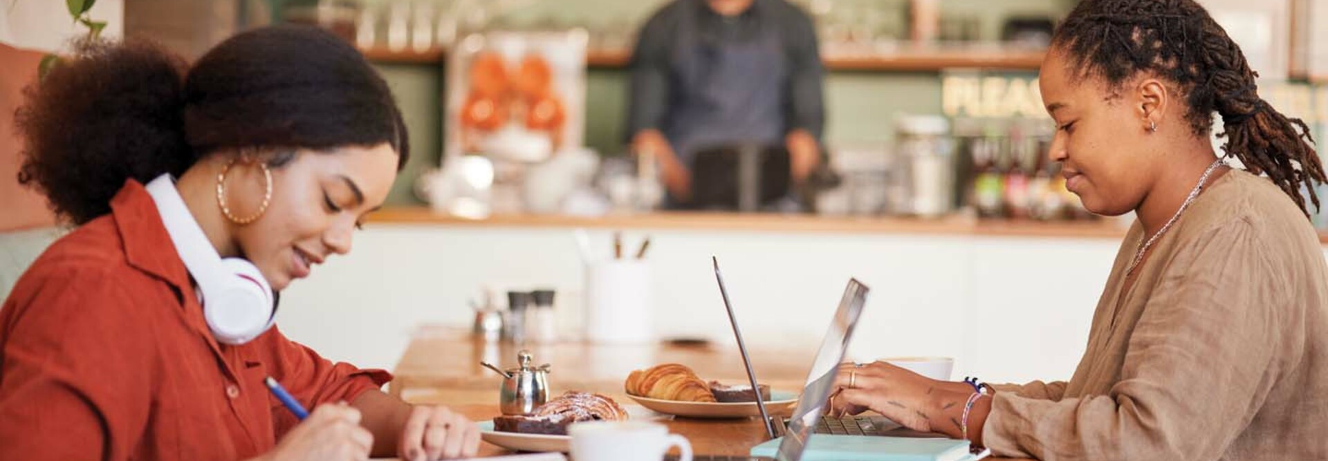 Two students work remotely in a coffee shop