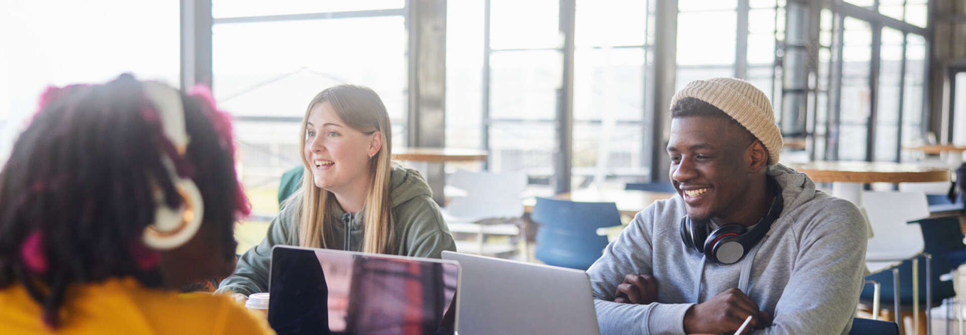 Diverse group of students smiling and studying at computers