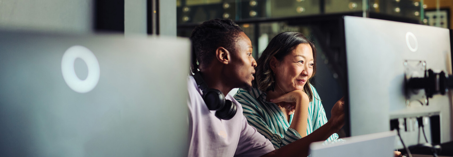 Two people work together at a desktop computer
