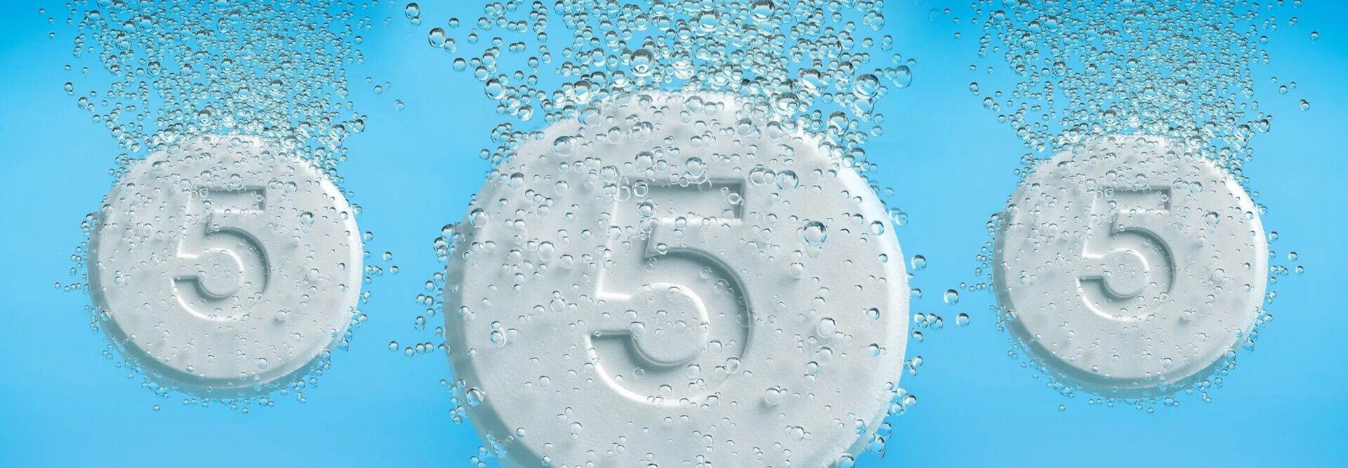 Tablets with the number five on them dropping into liquid and fizzing