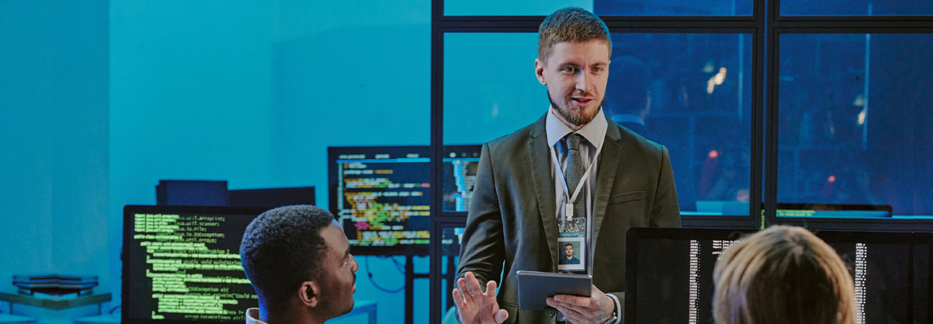 exec talking to 2 people in front of computer screens