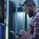 A man works on a tablet inside a large data center