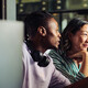 Two people work together at a desktop computer