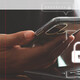A person with a phone in one hand and their other hand on a keyboard, presumably to complete multifactor authentication