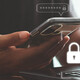 A person with a phone in one hand and their other hand on a keyboard, presumably to complete multifactor authentication