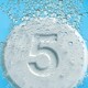 Tablets with the number five on them dropping into liquid and fizzing