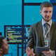 exec talking to 2 people in front of computer screens