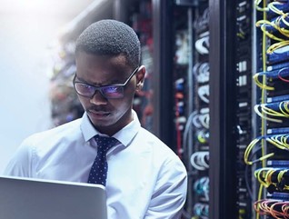 An IT worker on his laptop inside a data center