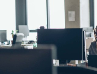 A woman works at a desk in a mostly empty office