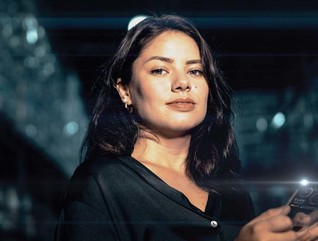 A woman holding a phone smiles at the camera in a futuristic setting