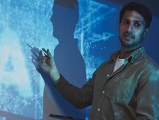 A man stands in front of an abstract representation of artificial intelligence