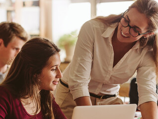 An instructor works with students in a classroom setting