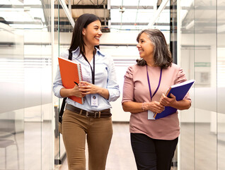 Two women chat about CIEM in an open hallway