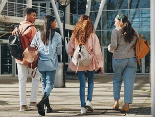 Rear angle photo of a group of students walking toward a campus building