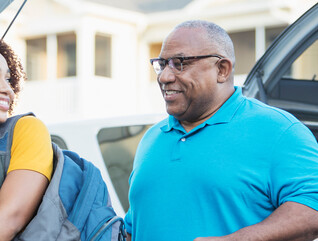 A student and and older adult unload a car during college move-in day