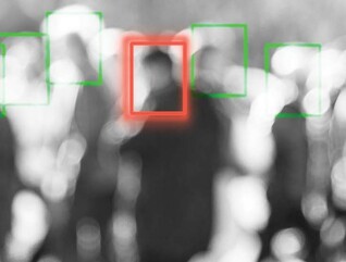 A blurred crowd of people whose faces are being scanned by an unseen camera
