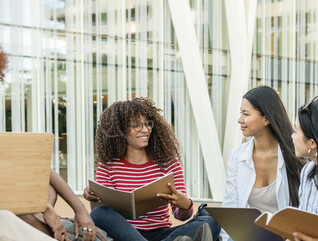 A group of students chat outside on a college campus