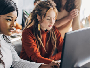 Two students working at computers in a classroom