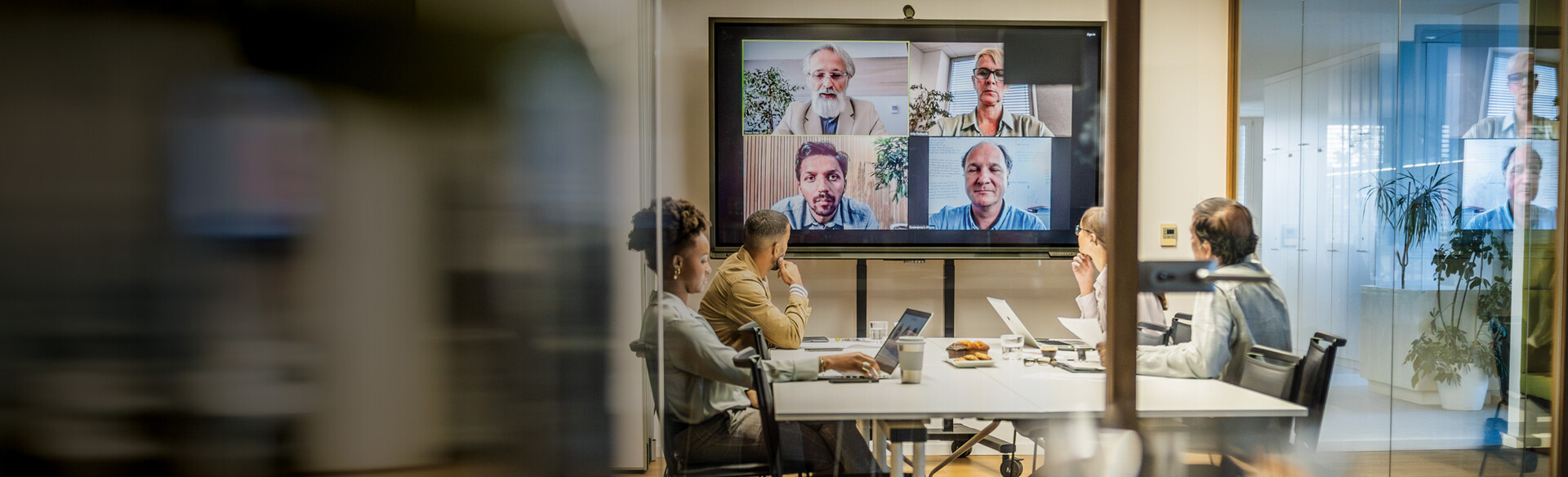 Several people seated a table have a call with remote employees