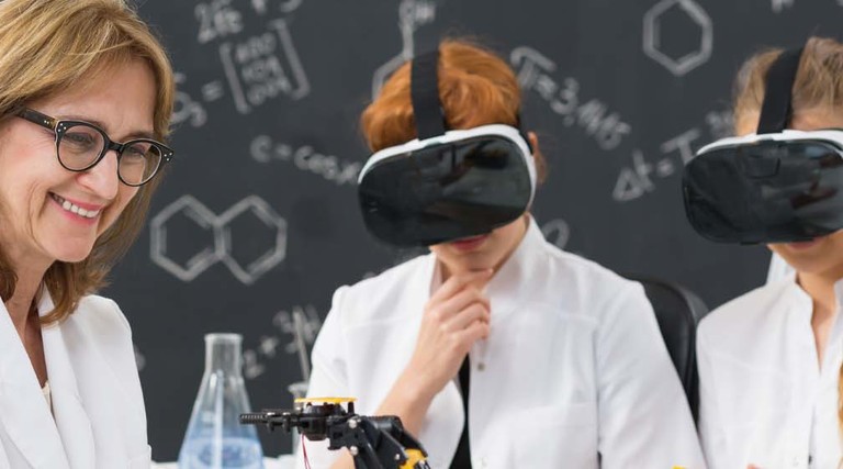 Two students wear VR headsets as their professor instructs