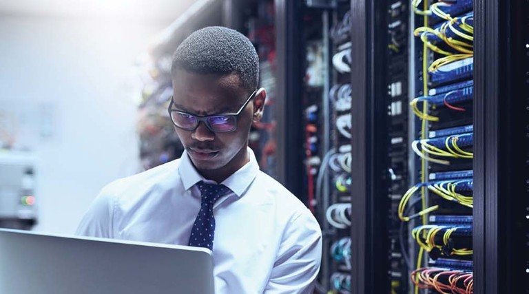 An IT worker on his laptop inside a data center